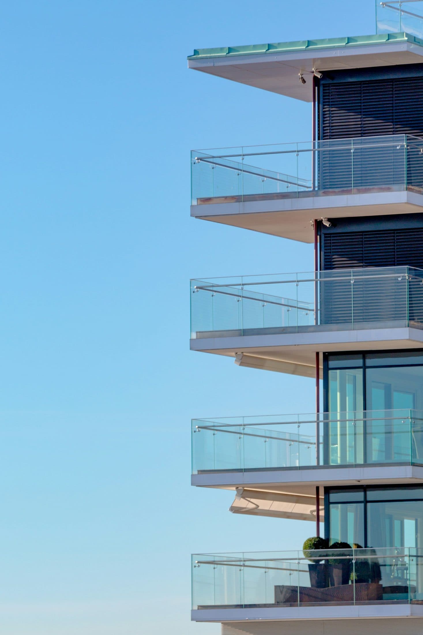Demo image. Glass balconies on a white building against the sky.